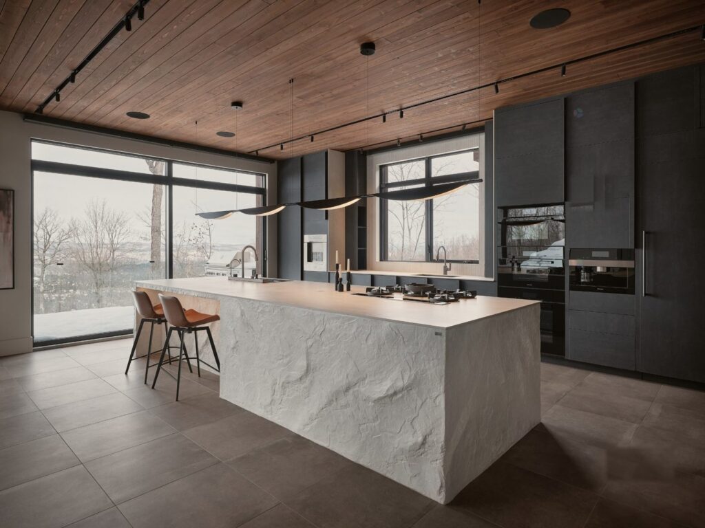 Cuisine avec îlot de pierre et commandes intégrées au mobilier, résidence des Laurentides